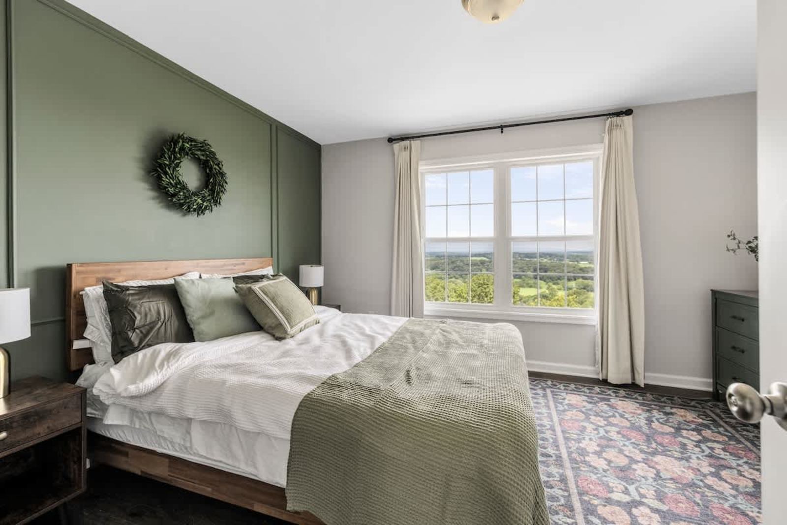 King bedroom with a sage accent wall and a panoramic valley view