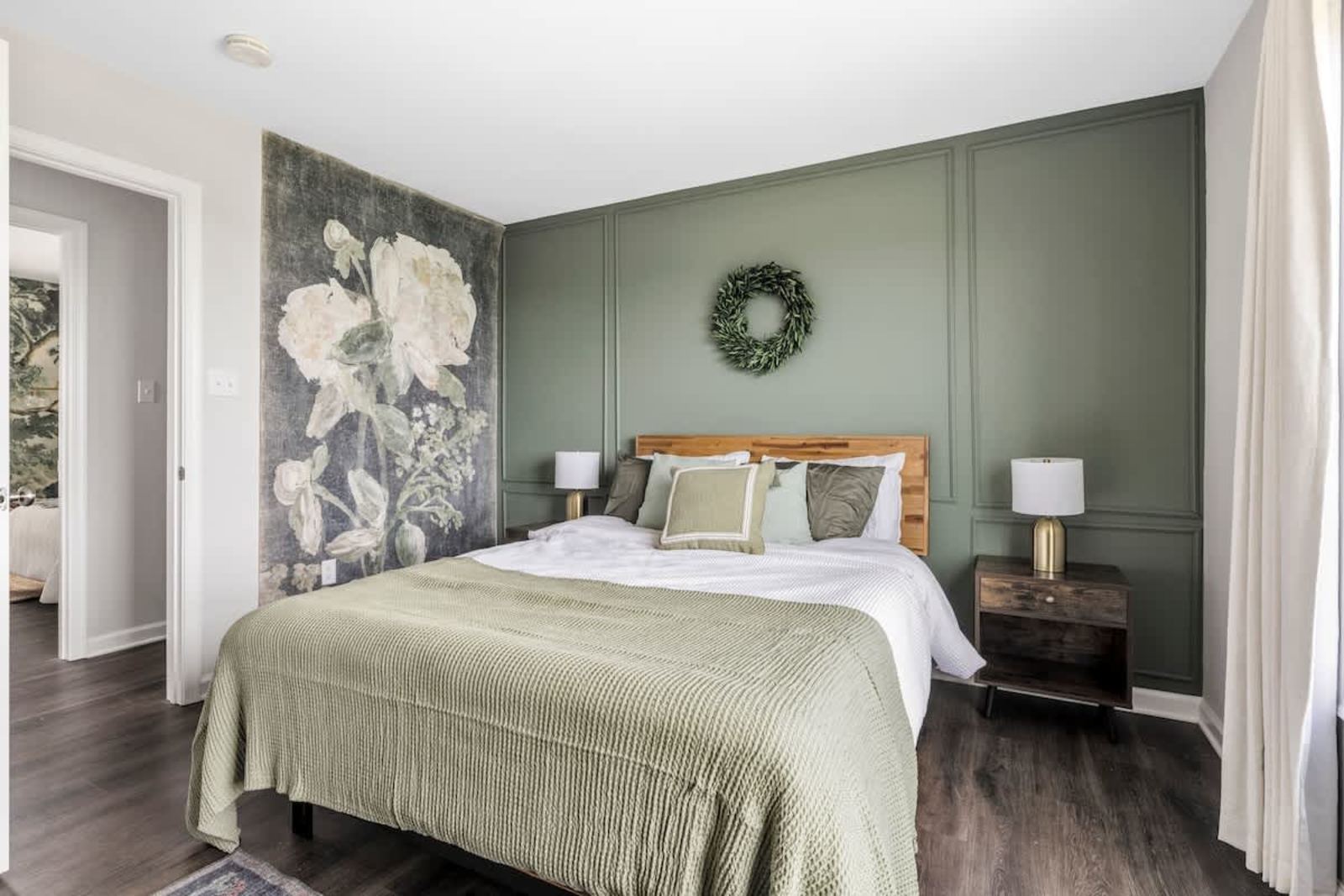 Bedroom with a sage paneled wall and a floral mural accent