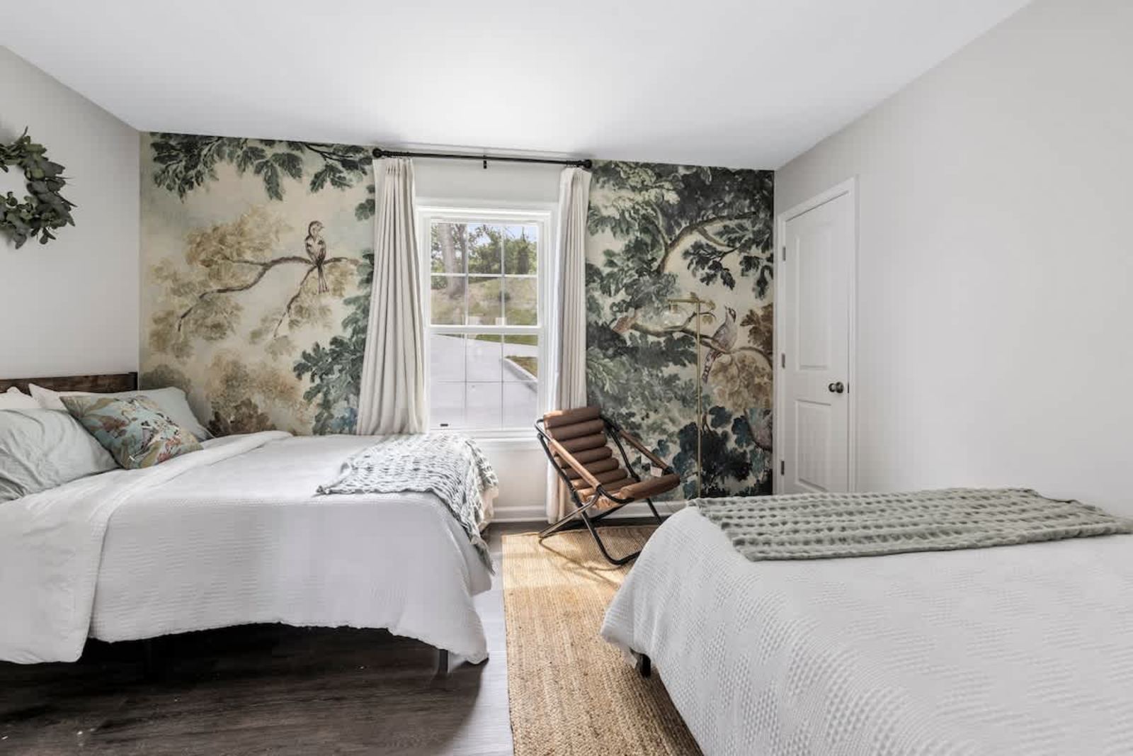Guest room with two beds, a botanical mural, and forest views