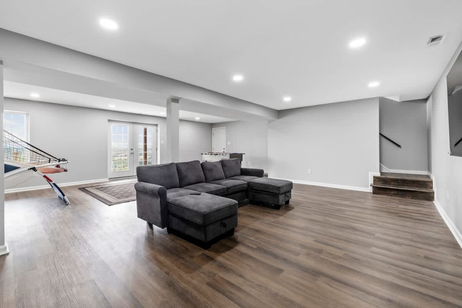Lower-level family room with a sectional, smart TV, and walkout doors